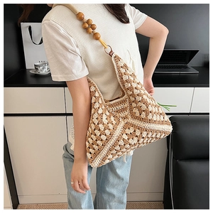 Detail of bohemian knit tote bag with wooden bead accents and hollow out pattern