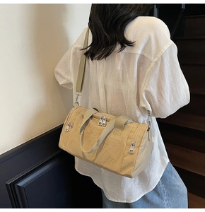 Detail of light beige nylon travel bag showing durable fabric and functional zippers