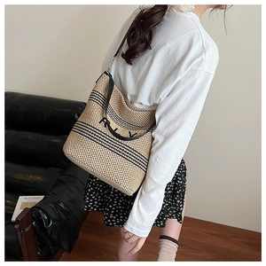 Détail d'un grand sac cabas tissé avec rayures noires et lanières en cuir chic