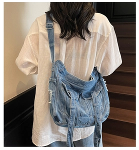 Detail of blue denim crossbody bag with distressed texture and vintage fringe accents