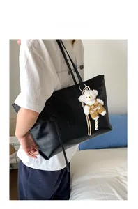 Detailed view of black crocodile pattern tote bag featuring a cute white bear charm