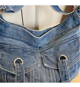 Detailed close-up of blue washed denim texture with orange stitching and silver hardware