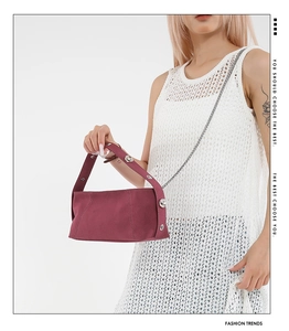 Detail of burgundy shoulder bag with metallic studs on white dress background
