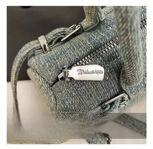 Macro shot of silver metal zipper and hardware on light blue denim baguette bag