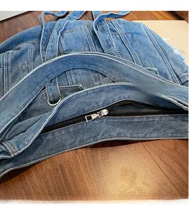 Detail shot of smooth silver metal zipper and stitching on blue denim crossbody bag