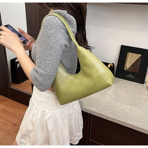 Model wearing a green crocodile pattern hobo shoulder bag in a minimalist indoor setting