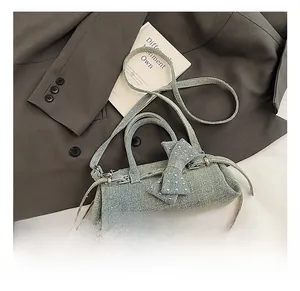 Detail of light blue denim pillow bag with rhinestone bow and crossbody strap