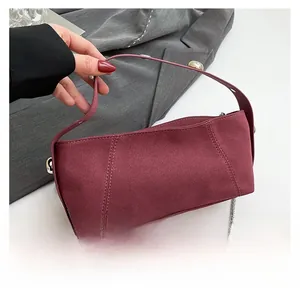 Detail view of burgundy suede shoulder bag featuring silver chain and matte texture finish