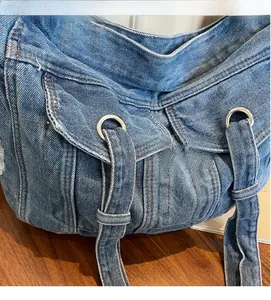 Detail of dark blue washed denim tote bag with silver rings and brown contrast stitching