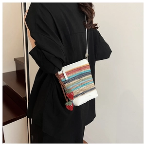 Détail du sac seau en paille arc-en-ciel avec breloques fraises et garniture en cuir blanc