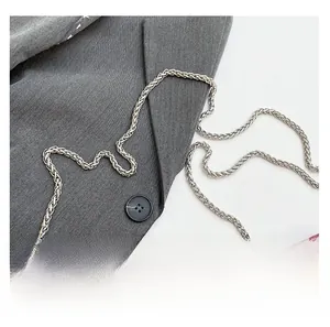Detailed macro view of a silver metal woven chain strap on a gray fabric bag surface