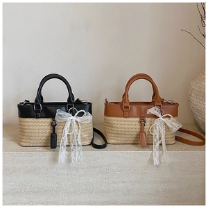 Detail view of woven straw tote bags with leather trim and decorative lace bow charm