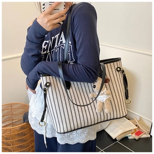 Detail of striped canvas tote bag featuring black leather trim and cute puppy charm