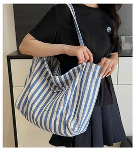 Close-up of blue and white striped canvas tote bag showing the exterior pocket and strap