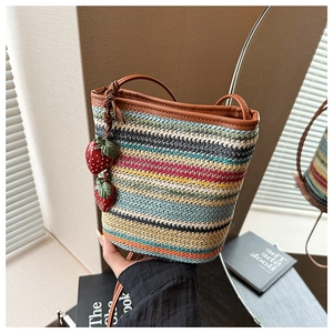 Détail du mini sac seau tissé coloré avec breloques fraises et bandoulière en cuir