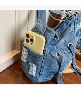 Detail of blue denim shoulder bag showing functional side pocket for smartphone storage