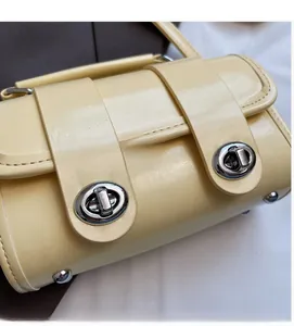 Dettaglio borsa in pelle giallo chiaro con chiusure girevoli in metallo argentato