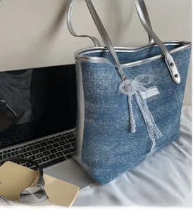 Dettaglio borsa tote in denim blu a pois con manici argentati e ciondolo a fiocco in pizzo