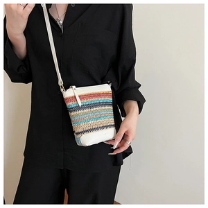 Close-up of rainbow striped straw woven bag featuring white leather trim and strap