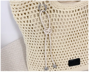 Detail of woven beige tote bag featuring silver ring hardware and a black leather logo patch