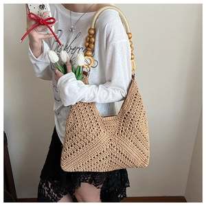 Detail of hand-woven straw bag featuring unique wooden bead handle and openwork texture