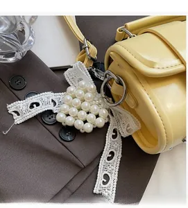 Dettaglio del ciondolo per borsa a cuore in perle con pizzo bianco su borsa gialla a cilindro