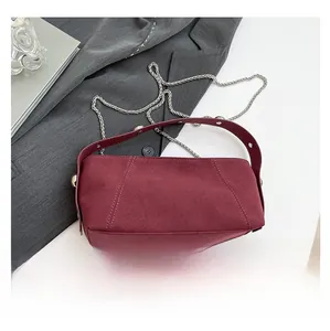 Detail of dark red matte leather handbag with silver chain strap on grey blazer