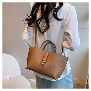 Brown lychee-textured tote bag shown on a model featuring gold metal hardware and strap