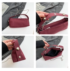 Detail of burgundy suede shoulder bag with silver spherical rivets and metal chain strap