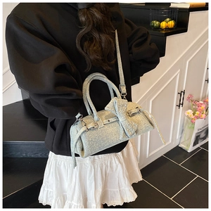 Chic light blue denim pillow bag with silver buckle and bow detail, worn cross-body