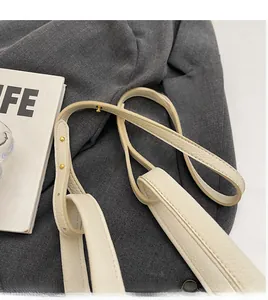 Close-up of lychee grain leather strap with gold adjustable studs on cream bucket bag
