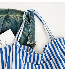 Close-up of wide canvas straps on a blue and white striped tote bag for daily commute