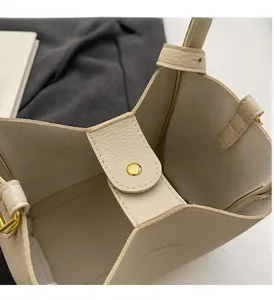 Detail of creamy white bucket bag with gold snap fastener and pebbled leather texture