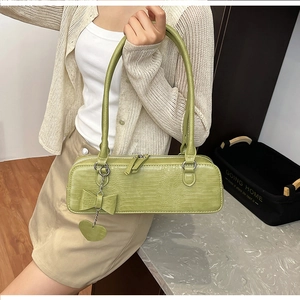 Détail de la texture croco vert clair et pendentif cœur sur un sac à main rectangulaire