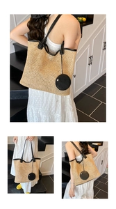 Close-up of woven straw tote bag featuring black faux leather trim and round charm