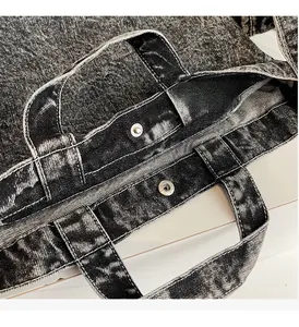 Detail of premium metal hardware on a dark grey vintage washed denim tote bag texture