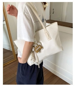 White crocodile pattern tote bag with a cute bear charm shown in a lifestyle setting