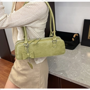Détail d'un sac à main vert clair gaufré crocodile avec pendentif papillon en métal
