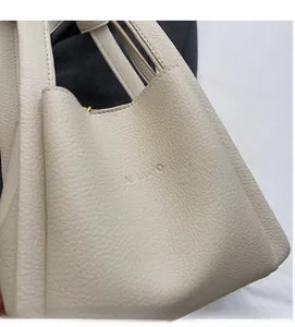 Close-up of cream white lychee texture leather handbag with embossed FAMUROO logo detail