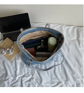 Vista dall'alto dell'ampio interno della borsa tote in denim blu con laptop e oggetti