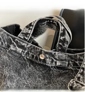 Close-up of denim tote bag handles with vintage metal snap and sturdy stitching details