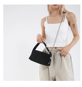Detail of black baguette bag with oversized silver studs and a metallic chain strap