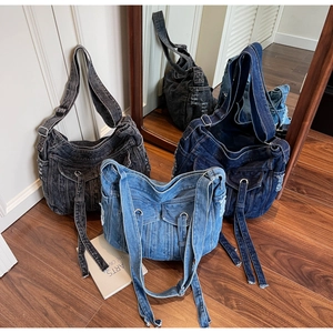 Detailed view of denim crossbody bags in black and blue with pockets and long fringe straps