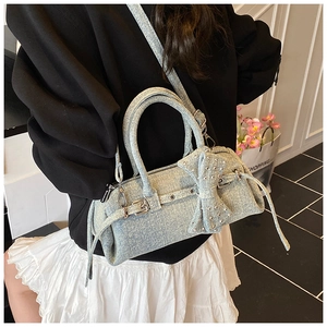 Detail of light blue denim pillow bag with silver rivets and large bow decoration