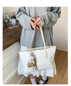Detail shot of white crocodile embossed texture on a large tote bag with bear charm