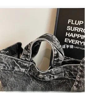 Detail of washed denim tote bag showing comfortable handle and silver metal snap button