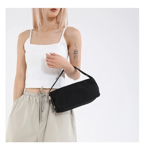Close-up of black canvas baguette bag with silver rivet details and side metal buckle