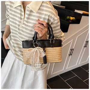 Close-up of straw woven tote with black leather trim and lace bow pearl charm detail