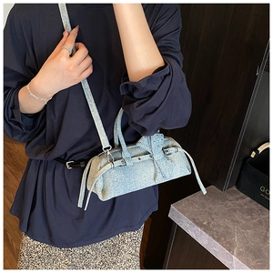 Detail of light blue denim pillow bag featuring a large bow and metallic rivet studs