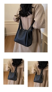 Detail of black lychee texture leather bucket bag with fashion lettering and strap